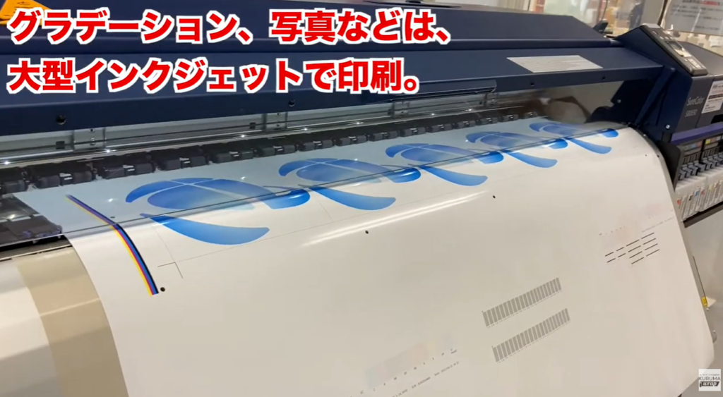 大型インクジェットプリンタで企業ロゴを印刷している写真